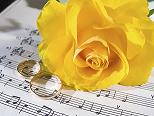 wedding rings and a yellow rose resting on sheet music